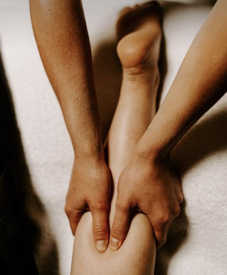 Hands resting at the calf during a lomilomi session